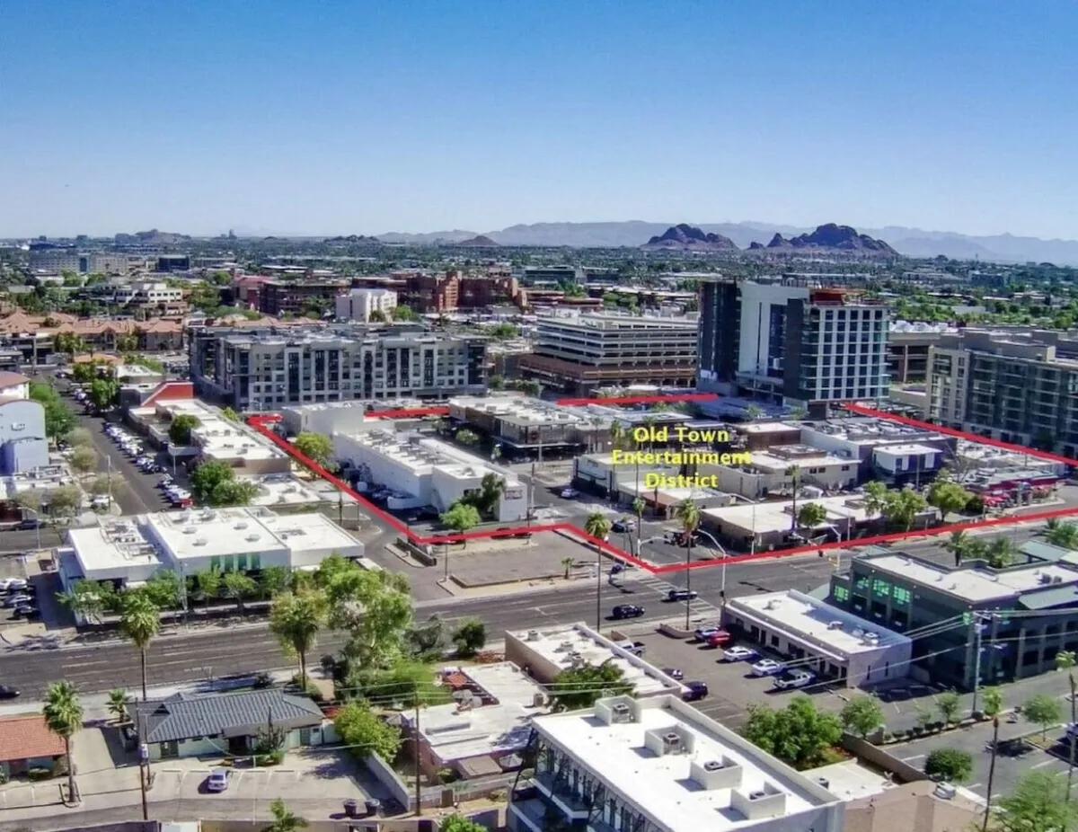 This lively exterior scene showcases the energetic atmosphere of Old Town's Entertainment District with modern buildings, bustling green spaces, and people engaged in shopping, dining, and entertainment. The image conveys the district's vibrant social life and walkable convenience.
