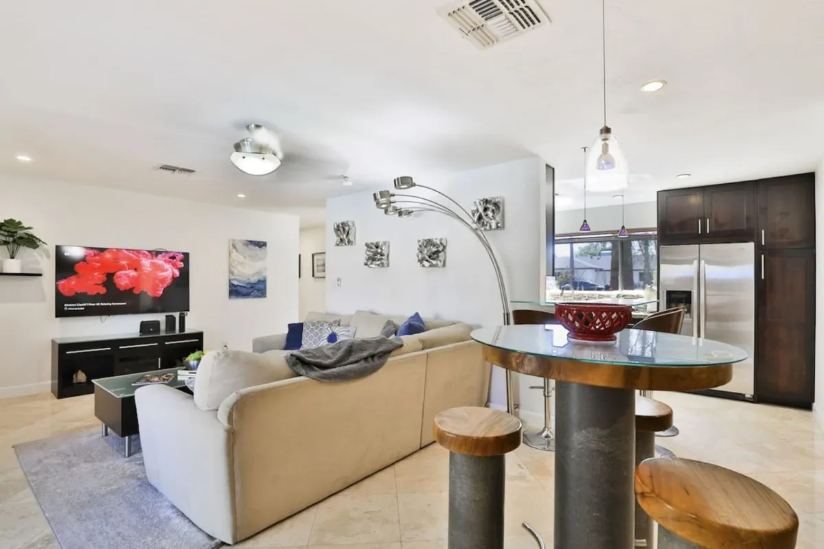 A comfortable lounge setup with a sofa, TV, bar table with stools, and eye-catching artwork on the wall. The space is casual yet stylish, ideal for hosting movie nights or enjoying cocktails before heading out, in line with the section's emphasis on flexible entertaining spaces.