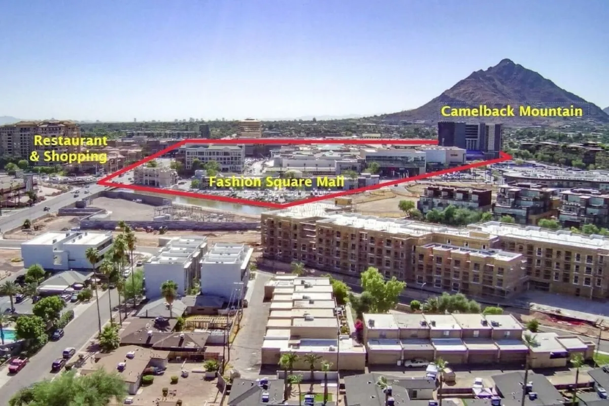 This exterior image captures the lively area surrounding Fashion Square Mall, with visible restaurant and shopping areas set against the backdrop of Camelback Mountain. Outdoor dining spaces and vibrant activity highlight Scottsdale’s culinary and social scene.