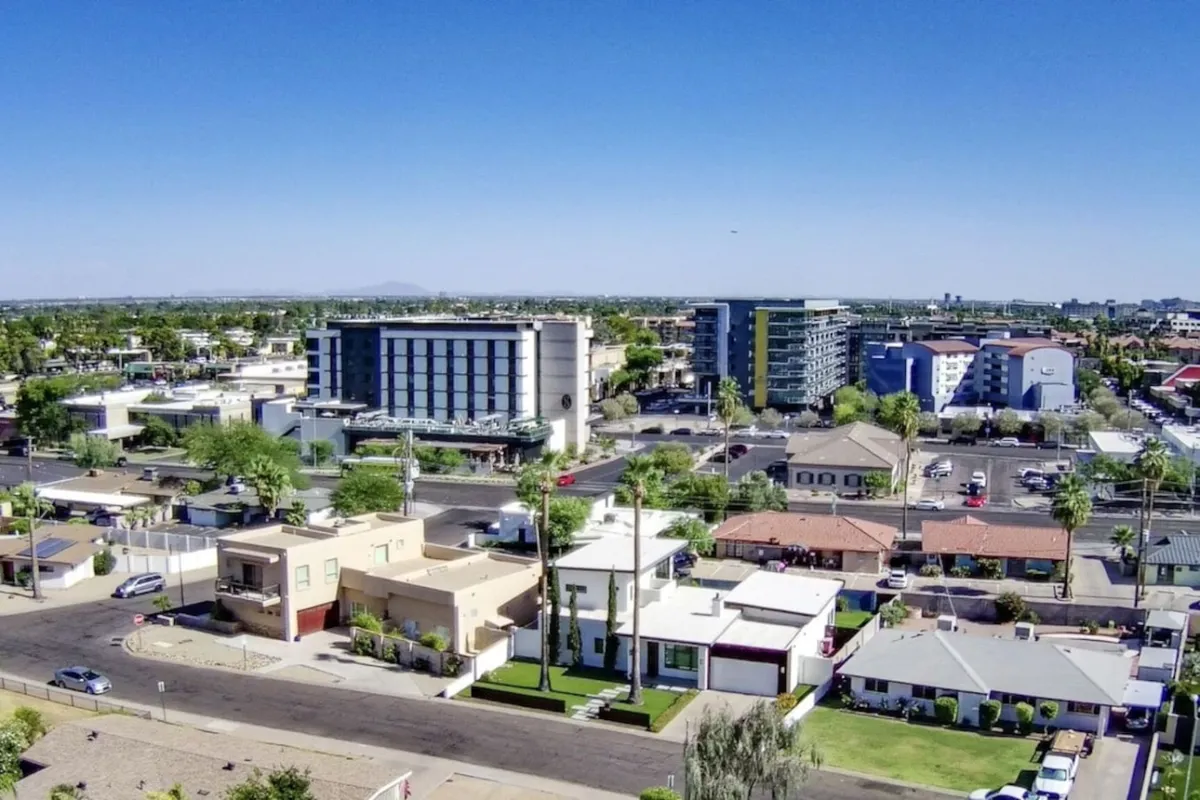 A street-level scene showcasing various residential buildings, bustling commercial establishments, lush green spaces, and iconic palm trees. The atmosphere is lively, with people engaging in shopping, visiting parks, and participating in community activities.