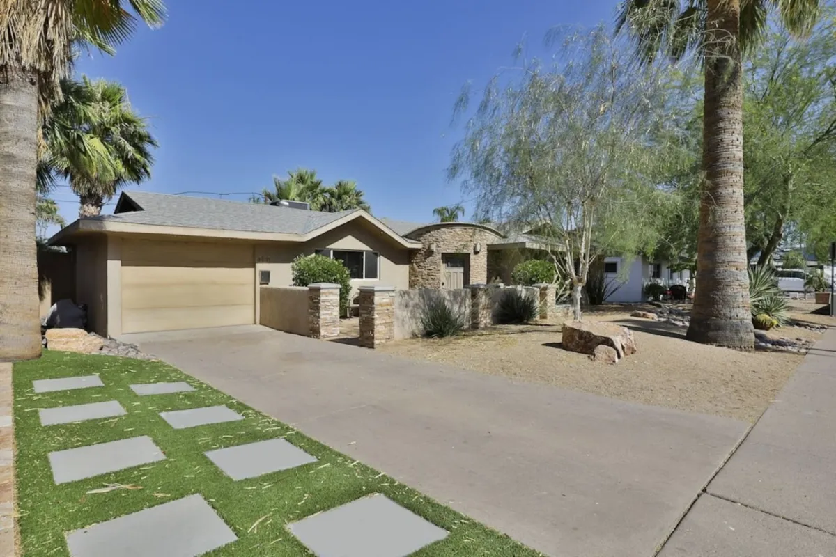 The home's welcoming stone facade and landscaped walkway, framed by tall palm trees. The image evokes a sense of arrival, inviting guests to start their Scottsdale experience right at the doorstep.