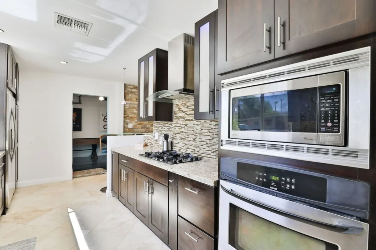 Contemporary kitchen interior with granite countertops, stainless steel appliances, and a decorative backsplash. The space is designed for cooking, entertaining, and family gatherings, exuding a sense of functionality and style ideal for culinary enthusiasts.